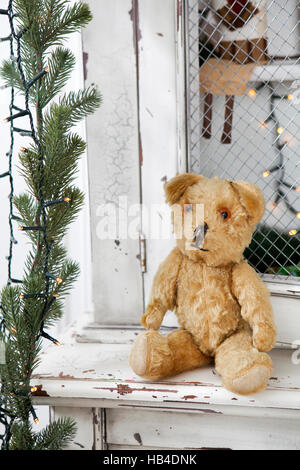 Vintage credenza con giocattoli di Natale e albero di Natale ghirlanda. Vintage teddy-bear seduta sul guardaroba Foto Stock