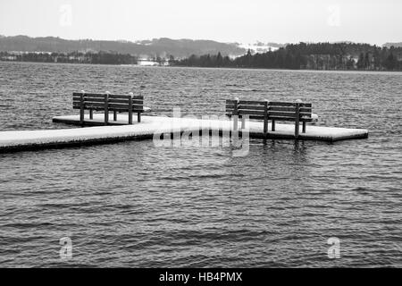 Bianco e nero colpo di due panche su un molo al tempo di inverno Foto Stock