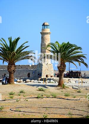 Vista del faro incorniciato da palme con i turisti lungo la parete del porto, Rethimno, Creta, Grecia, l'Europa. Foto Stock