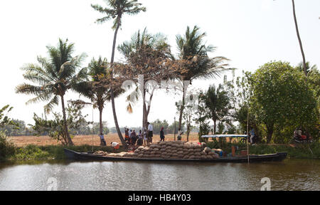 Barca di riso essendo caricato con sacchi di riso dai campi di risone in riso area della cinghia del Kerala, India Foto Stock