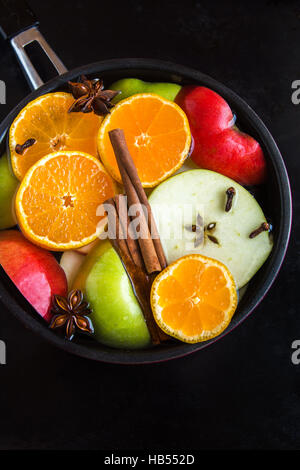 Apple Mulled sidro arancione (punch) in padella su sfondo nero, vista dall'alto - cottura lenta piccante di festa in casa bevanda Foto Stock