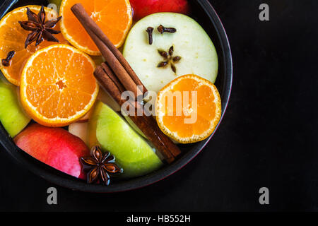 Apple Mulled sidro arancione (punch) in padella su sfondo nero, vista dall'alto - cottura lenta piccante di festa in casa bevanda Foto Stock