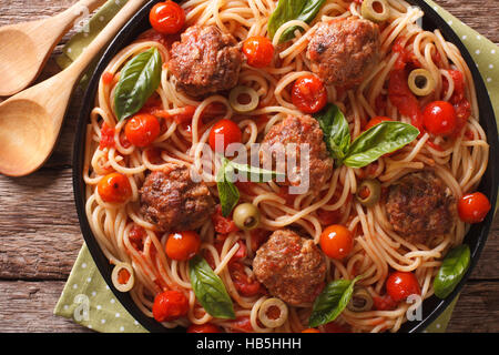 Il cibo italiano: gli spaghetti con le polpette di carne, olive, basilico e salsa di pomodoro closeup su una piastra. Vista orizzontale dal di sopra Foto Stock