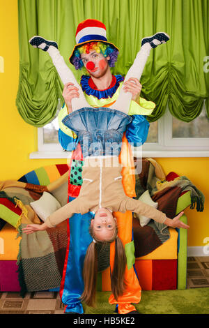 Clown detiene la bambina Head over heels. Foto Stock