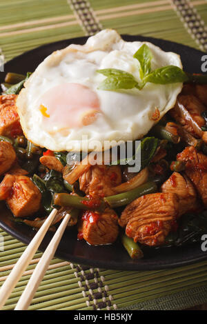 Thai Gai Pad Krapow il pollo con il basilico e le uova di close-up su una piastra verticale Foto Stock