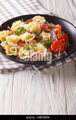 Cucinata fresca tortellini con prosciutto e formaggio parmigiano close-up su una piastra. In verticale Foto Stock