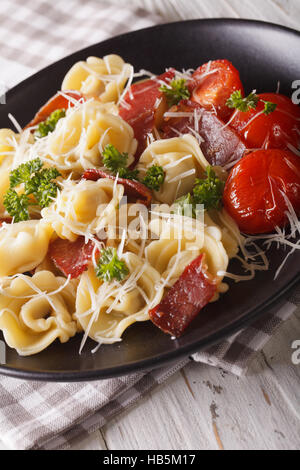 Italian tortellini con prosciutto e formaggio parmigiano close-up su una piastra verticale. Foto Stock