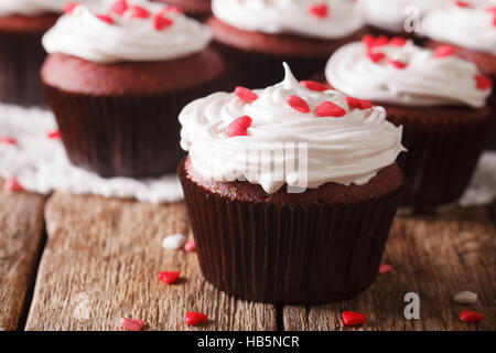 Festosa di velluto rosso tortine decorate con cuori macro sul tavolo orizzontale. Foto Stock