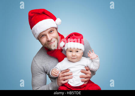 Padre con il suo bambino indossando cappelli di Babbo Natale festeggiano il Natale Foto Stock