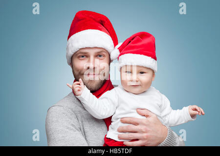 Padre con il suo bambino indossando cappelli di Babbo Natale festeggiano il Natale Foto Stock