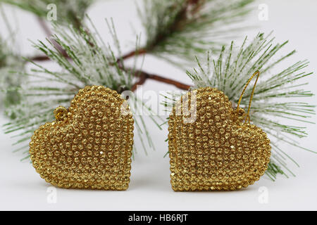 Due a forma di cuore ad golden baubles e pini coperti di neve Foto Stock