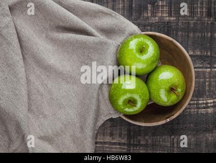 Verde mele sano nella ciotola di legno cucina panno sullo sfondo di legno Foto Stock