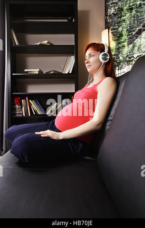 Donna incinta ascoltando musica Foto Stock