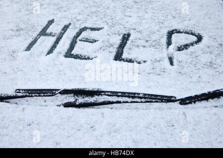 Coperta di neve auto parabrezza con la parola help scritto nella neve Foto Stock