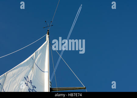 La ricerca di un montante di yacht con un aereo di linea e contrails in perfettamente chiaro cielo blu