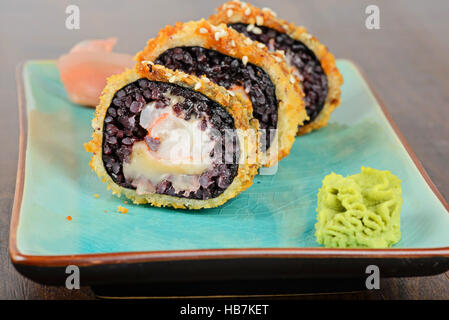 Cotto rotoli di sushi servita sulla piastra blu Foto Stock