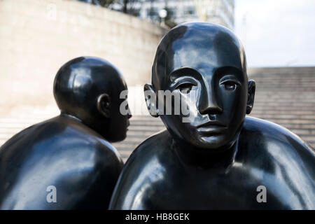 Due uomini su un banco da Giles Penny, scultura in bronzo a Canary Wharf, London, Regno Unito Foto Stock