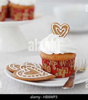 Spice cupcake con glassa alla vaniglia e gingerbread cookie cuori per Natale Foto Stock