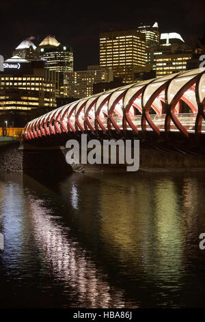 Peace Bridge con pannelli di vetro sul tetto illuminato di notte, il ponte attraversa il fiume Bow dal centro di Calgary. Foto Stock