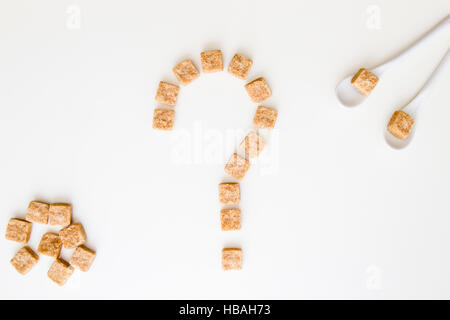 Rosolare i cubetti di zucchero a forma di punto interrogativo su sfondo bianco. Vista dall'alto. Dieta dolce unhealty concetto di dipendenza Foto Stock
