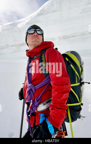 Ritratto di uomo con attrezzatura per alpinismo guardando lontano Foto Stock