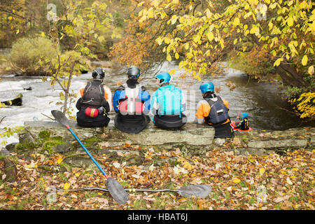 Vista posteriore di kayakers guardando fuori dalla banca del fiume parete, fiume Dee, Llangollen, il Galles del Nord Foto Stock