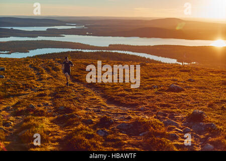 Uomo che corre sulla Scogliera al tramonto, Keimiotunturi, Lapponia, Finlandia Foto Stock