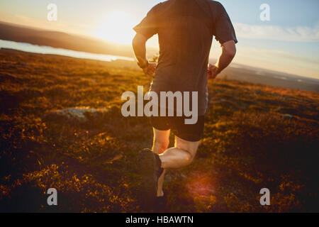 Uomo che corre sulla Scogliera al tramonto, Keimiotunturi, Lapponia, Finlandia Foto Stock