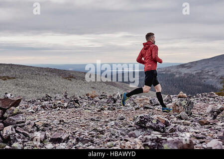 Uomo che corre sulla scogliera rocciosa top, Kesankitunturi, Lapponia, Finlandia Foto Stock