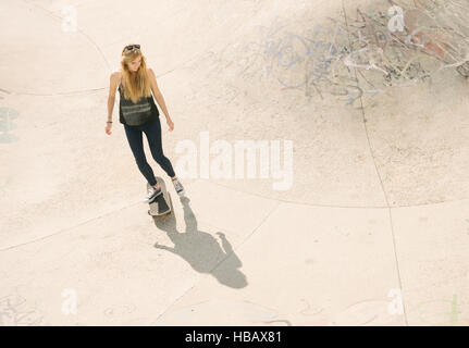 Elevato angolo di giovani femmine guidatore di skateboard skateboard in skatepark Foto Stock