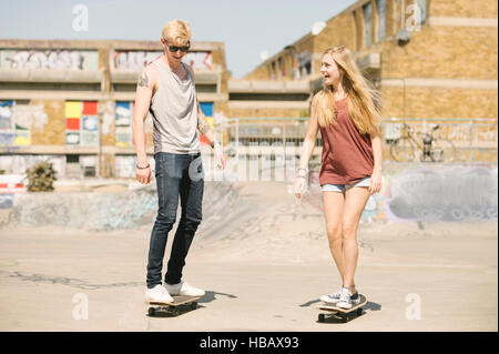 I giovani di sesso maschile e femminile per la corsa su skateboard skateboard amici in skatepark Foto Stock