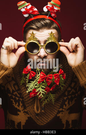 Divertenti uomo barbuto in un nuovo anno di immagine come Babbo Natale con decorazioni sulla sua barba. Festa di Natale. Foto Stock