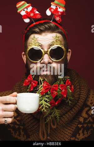 Divertenti uomo barbuto in un nuovo anno di immagine come Babbo Natale con decorazioni sulla sua barba. Festa di Natale. Foto Stock