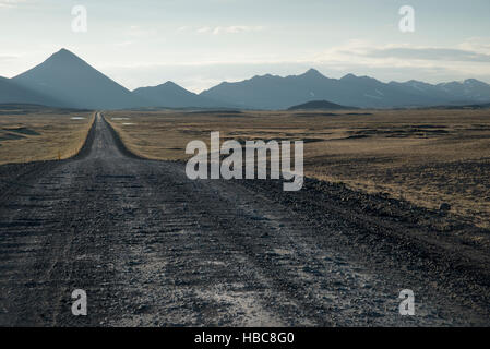 Una strada sterrata attraverso i vasti altopiani di Islanda che conducono verso la piramide montagne. Silhouette. Foto Stock