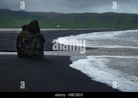White onde si infrangono contro lonely roccia basaltica e nero spiaggia vulcanica