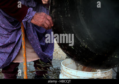 Nablus, West Bank, Palestina. 5 Dic, 2016. Un'anziana donna palestinese mescolare olio di oliva con acqua e sodio alcalino per fare il sapone a casa sua in Cisgiordania villaggio di Sarrah, nei pressi di Nablus City, 05 dicembre 2016. Le donne palestinesi hanno stanziato porzioni di ogni anno la raccolta delle olive per la produzione di sapone in una tradizione che risale ben oltre mille anni. Nabuls sapone è un tipo di sapone di Castiglia prodotto solo a Nablus in Cisgiordania, il suo capo gli ingredienti sono olio di oliva vergine (il principale prodotto agricolo della regione), acqua, e un metallo alcalino composto di sodio. Foto Stock