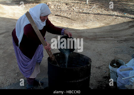 Nablus, West Bank, Palestina. 5 Dic, 2016. Un'anziana donna palestinese mescolare olio di oliva con acqua e sodio alcalino per fare il sapone a casa sua in Cisgiordania villaggio di Sarrah, nei pressi di Nablus City, 05 dicembre 2016. Le donne palestinesi hanno stanziato porzioni di ogni anno la raccolta delle olive per la produzione di sapone in una tradizione che risale ben oltre mille anni. Nabuls sapone è un tipo di sapone di Castiglia prodotto solo a Nablus in Cisgiordania, il suo capo gli ingredienti sono olio di oliva vergine (il principale prodotto agricolo della regione), acqua, e un metallo alcalino composto di sodio. Foto Stock