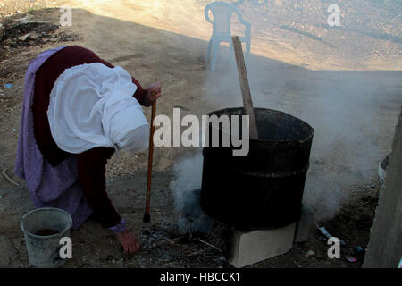 Nablus, West Bank, Palestina. 5 Dic, 2016. Un'anziana donna palestinese mescolare olio di oliva con acqua e sodio alcalino per fare il sapone a casa sua in Cisgiordania villaggio di Sarrah, nei pressi di Nablus City, 05 dicembre 2016. Le donne palestinesi hanno stanziato porzioni di ogni anno la raccolta delle olive per la produzione di sapone in una tradizione che risale ben oltre mille anni. Nabuls sapone è un tipo di sapone di Castiglia prodotto solo a Nablus in Cisgiordania, il suo capo gli ingredienti sono olio di oliva vergine (il principale prodotto agricolo della regione), acqua, e un metallo alcalino composto di sodio. Foto Stock