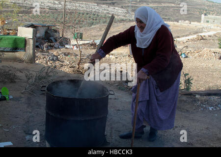 Nablus, West Bank, Palestina. 5 Dic, 2016. Un'anziana donna palestinese mescolare olio di oliva con acqua e sodio alcalino per fare il sapone a casa sua in Cisgiordania villaggio di Sarrah, nei pressi di Nablus City, 05 dicembre 2016. Le donne palestinesi hanno stanziato porzioni di ogni anno la raccolta delle olive per la produzione di sapone in una tradizione che risale ben oltre mille anni. Nabuls sapone è un tipo di sapone di Castiglia prodotto solo a Nablus in Cisgiordania, il suo capo gli ingredienti sono olio di oliva vergine (il principale prodotto agricolo della regione), acqua, e un metallo alcalino composto di sodio. Foto Stock