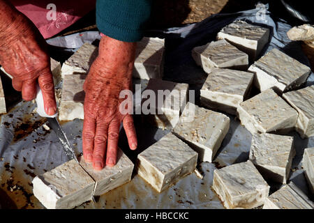 Nablus, West Bank, Palestina. 5 Dic, 2016. Un'anziana donna palestinese mescolare olio di oliva con acqua e sodio alcalino per fare il sapone a casa sua in Cisgiordania villaggio di Sarrah, nei pressi di Nablus City, 05 dicembre 2016. Le donne palestinesi hanno stanziato porzioni di ogni anno la raccolta delle olive per la produzione di sapone in una tradizione che risale ben oltre mille anni. Nabuls sapone è un tipo di sapone di Castiglia prodotto solo a Nablus in Cisgiordania, il suo capo gli ingredienti sono olio di oliva vergine (il principale prodotto agricolo della regione), acqua, e un metallo alcalino composto di sodio. Foto Stock