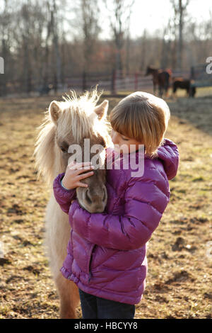 Ragazza giovane all'aperto, avvolgente pony Foto Stock