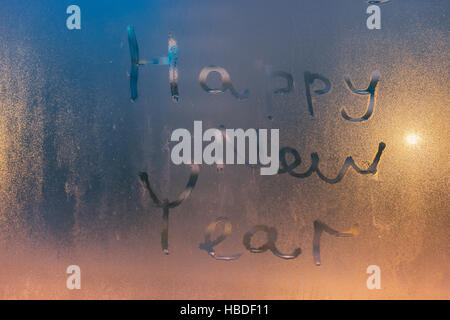 Felice anno nuovo testo scritto sul vetro steamy. Scuro dello sfondo colorato Foto Stock