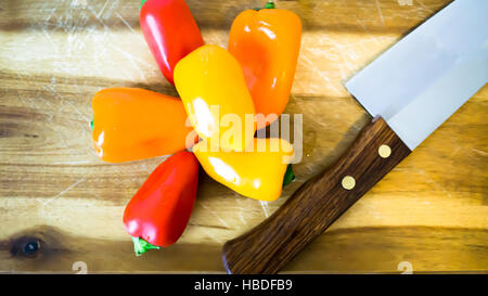 La paprica mista e il coltello su un tagliere Foto Stock