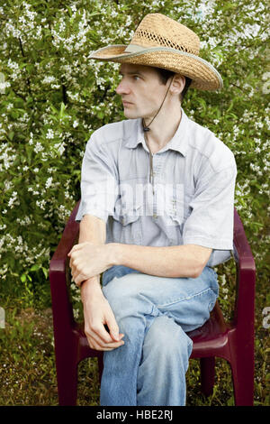 Un giovane uomo in un giardino di ciliegie Foto Stock