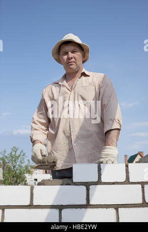 Muratore costruisce un muro Foto Stock