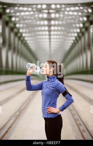 Giovani runner in appoggio, acqua potabile verde sul ponte in acciaio Foto Stock