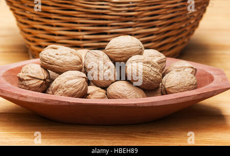 Noci (Juglans regia) in una ciotola di legno su una tavola di legno Foto Stock