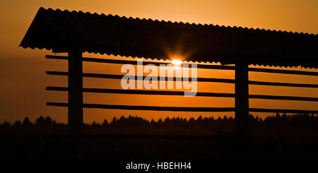 Estate tramonto dietro Kozolec (rack per fieno di asciugatura), Spodnji Brnik, Slovenia. Il Kozolec è una visione comune in Slovenia. Foto Stock