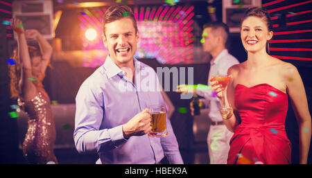 Immagine composita della coppia sorridente tenendo un bicchiere di birra e un cocktail mentre balli Foto Stock