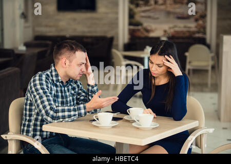 Coppia giovane sostenendo in una caffetteria. Lei ne ha avuto abbastanza, ragazzo è importante scusarsi. Problemi di relazione. Foto Stock